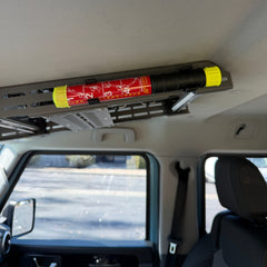 Element E50 fire extinguisher mounted in two Nylon 12 clips along the Cabdok in an Ineos Grenadier, seen from the drivers seat looking towards passenger seat