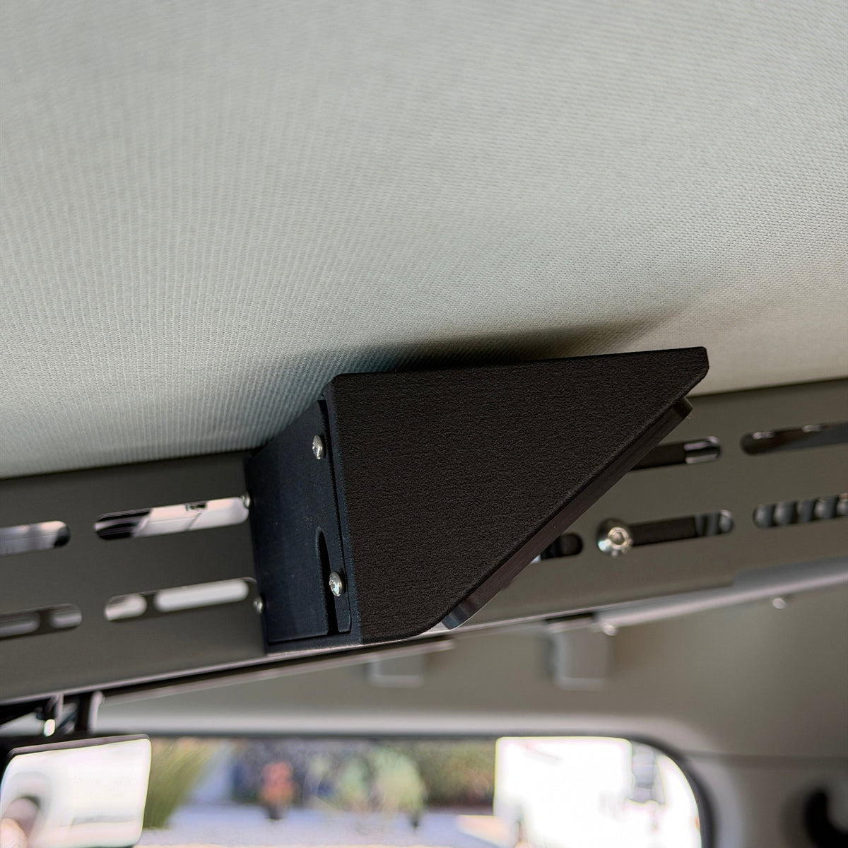 Side view of the Cabdok Switch-Pros Mount attached to the Cabdok side panel with screws, in an Ineos Grenadier overhead console