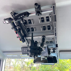 Cabdok overhead storage mount in Ineos Grenadier viewed from below, holding phone mount, radio, and flashlight